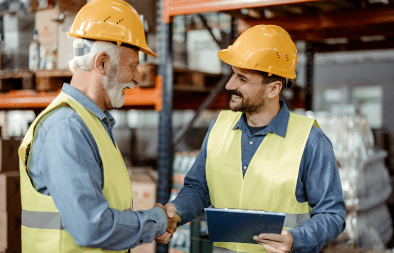 Two freight transportation professionals shaking hands in a warehouse
