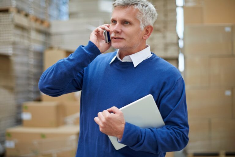 Man working for a freight carrier talking on the phone, coordinating a freight shipment.